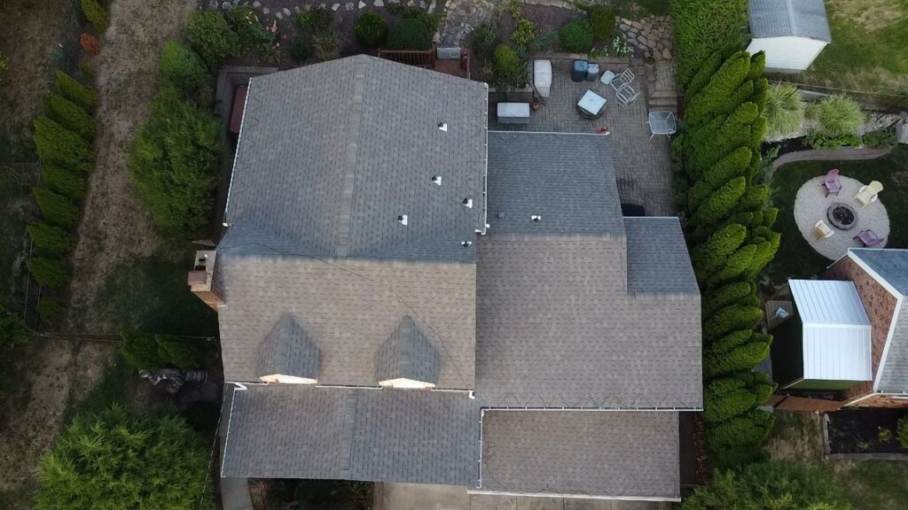 Aerial view of a residential roof in Pittsburgh, showcasing a well-maintained shingle roof with multiple vents and surrounding greenery, relevant to roofing services and maintenance tips for homeowners.