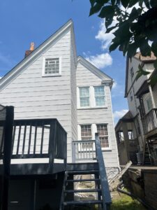 Residential building exterior with gray siding and white windows, showcasing a staircase and deck, relevant to roofing and siding services in Wexford, PA.