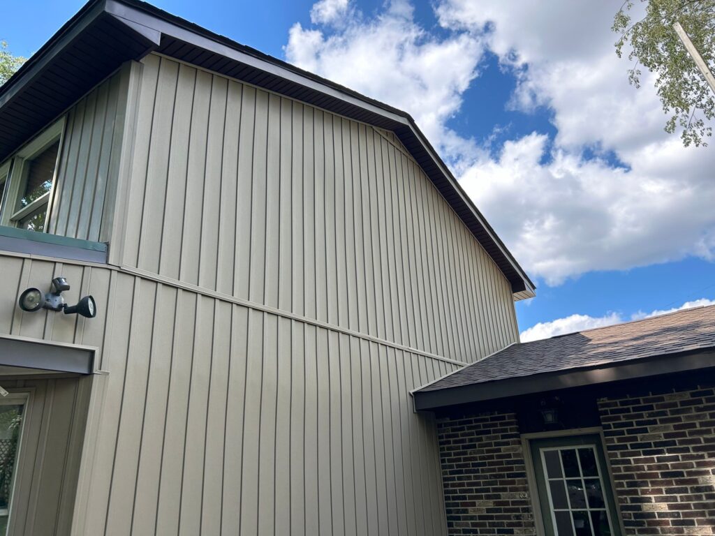 Exterior of a modern split-level home in Pittsburgh, showcasing vertical siding, a sloped roof, and clear blue sky, highlighting architectural features relevant to local roofing solutions.