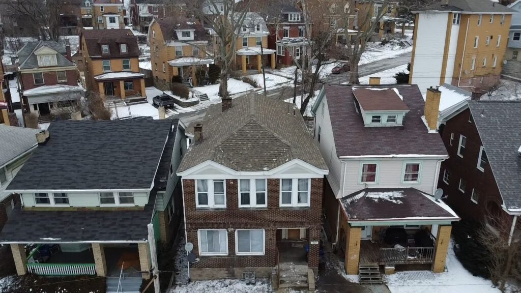 Aerial view of residential homes in Pittsburgh, Pennsylvania, showcasing various roofing styles and materials, relevant to homeowners considering roofing services and maintenance.