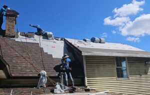 Roofing crew working on a residential roof in Pittsburgh, showcasing safety practices and maintenance work on a sunny day.