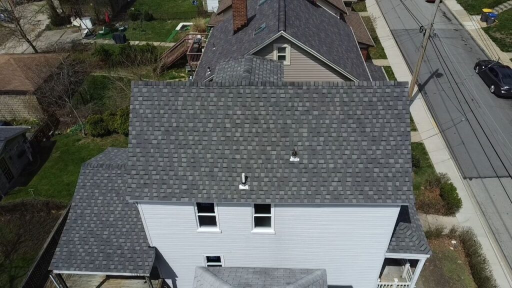 Aerial view of a residential roof in Pittsburgh, showcasing new asphalt shingles and surrounding neighborhood features, emphasizing roofing quality and home maintenance.