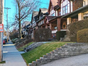 Charming residential street in Pittsburgh's Squirrel Hill neighborhood featuring classic architecture, well-maintained lawns, and tree-lined sidewalks, reflecting the community's character and appeal for homeowners.