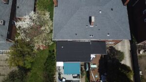 Aerial view of a residential roof in Bridgeville, PA, showcasing shingles and surrounding greenery, highlighting the importance of roofing maintenance for storm protection.