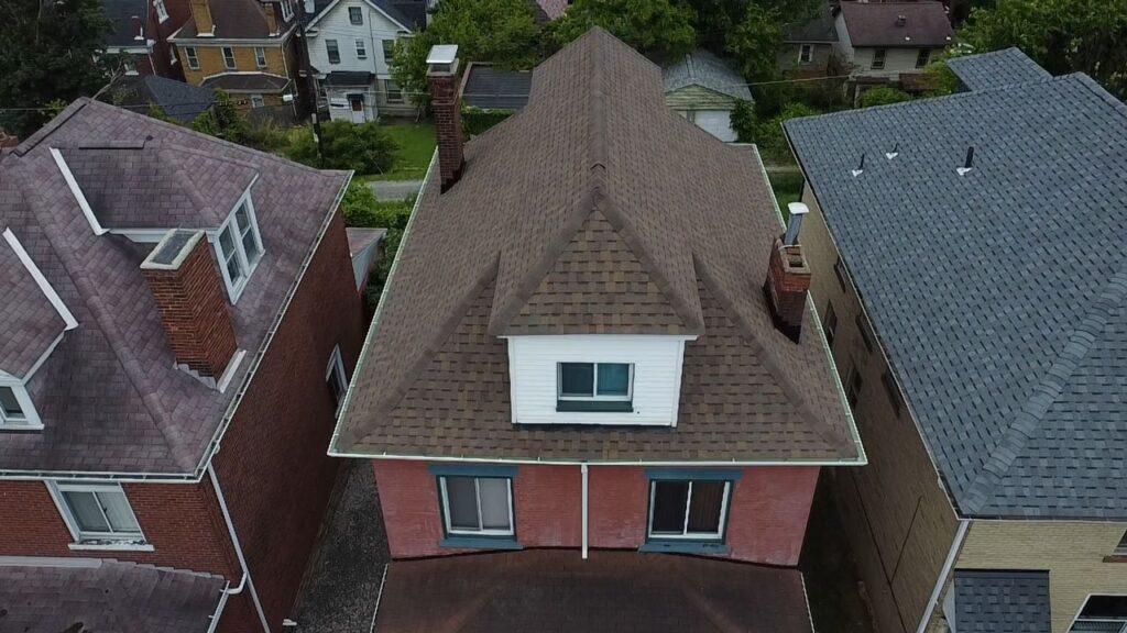 Aerial view of a residential home in Robinson Township, showcasing a well-maintained roof with shingles and a chimney, surrounded by neighboring houses, emphasizing the importance of roofing in enhancing home aesthetics.