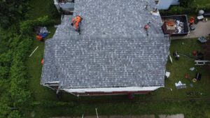 Roofing project in Pittsburgh, workers installing shingles on a residential roof, showcasing home improvement and maintenance in the Greenfield neighborhood.