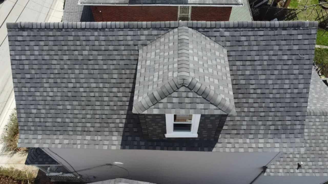 Aerial view of a newly installed gray shingle roof on a residential building, showcasing quality roofing craftsmanship relevant to Alan Construction's services in Pittsburgh.
