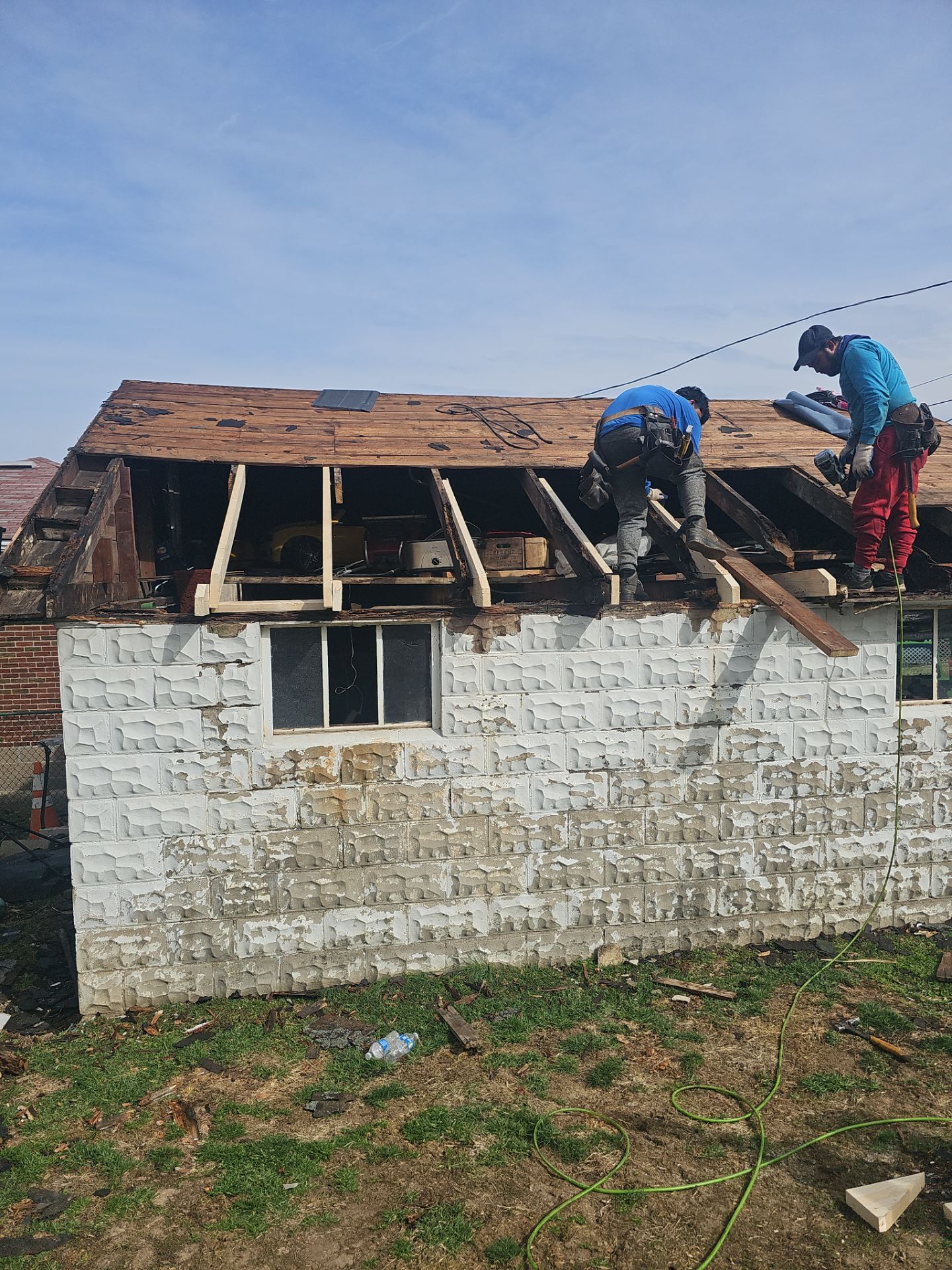 Workers removing old roof shingles and preparing a garage roof for replacement in Beechview, showcasing the ongoing garage roof replacement project by Alan Construction.