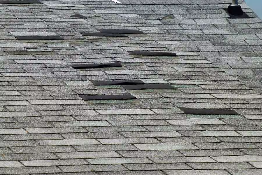 Asphalt shingle roof with multiple curled, lifted, and damaged shingles.