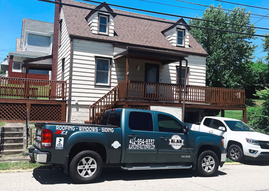 Residential home with a roofing and siding contractor&rsquo;s truck parked out front.