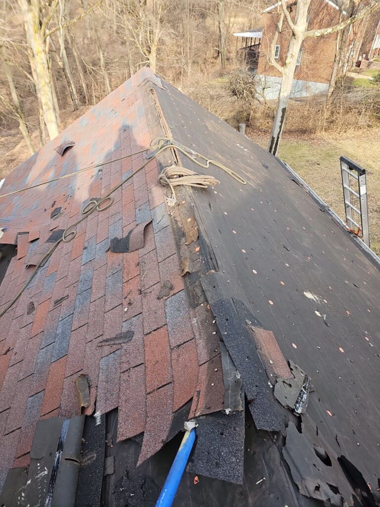 Old red shingles being torn off a Brentwood Cape Cod roof