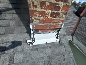 New white aluminum flashing wrapped around the base of a red brick chimney in Pittsburgh, Alan Construction