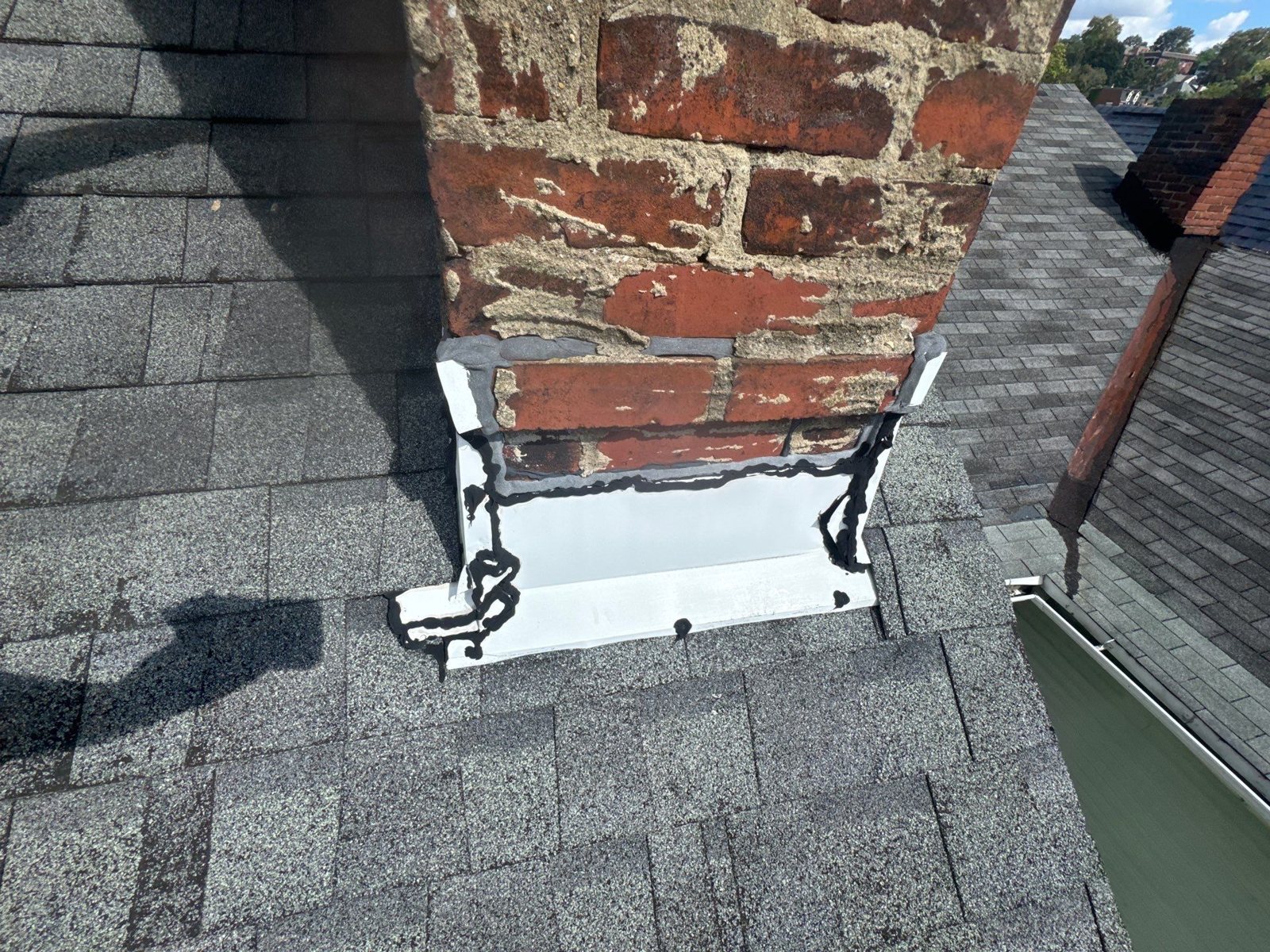 New white aluminum flashing wrapped around the base of a red brick chimney in Pittsburgh, Alan Construction