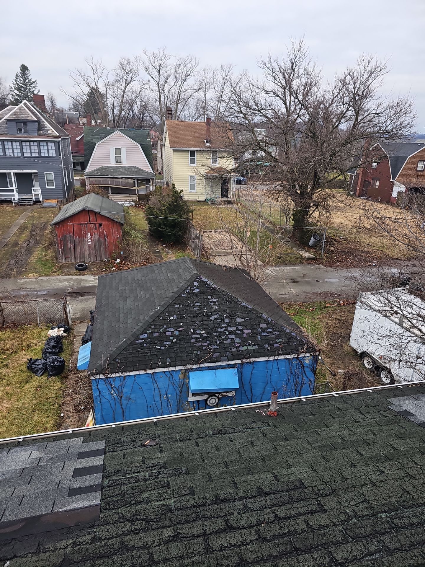 High view of an old shingle roof with a dumpster below in Clairton, Alan Construction
