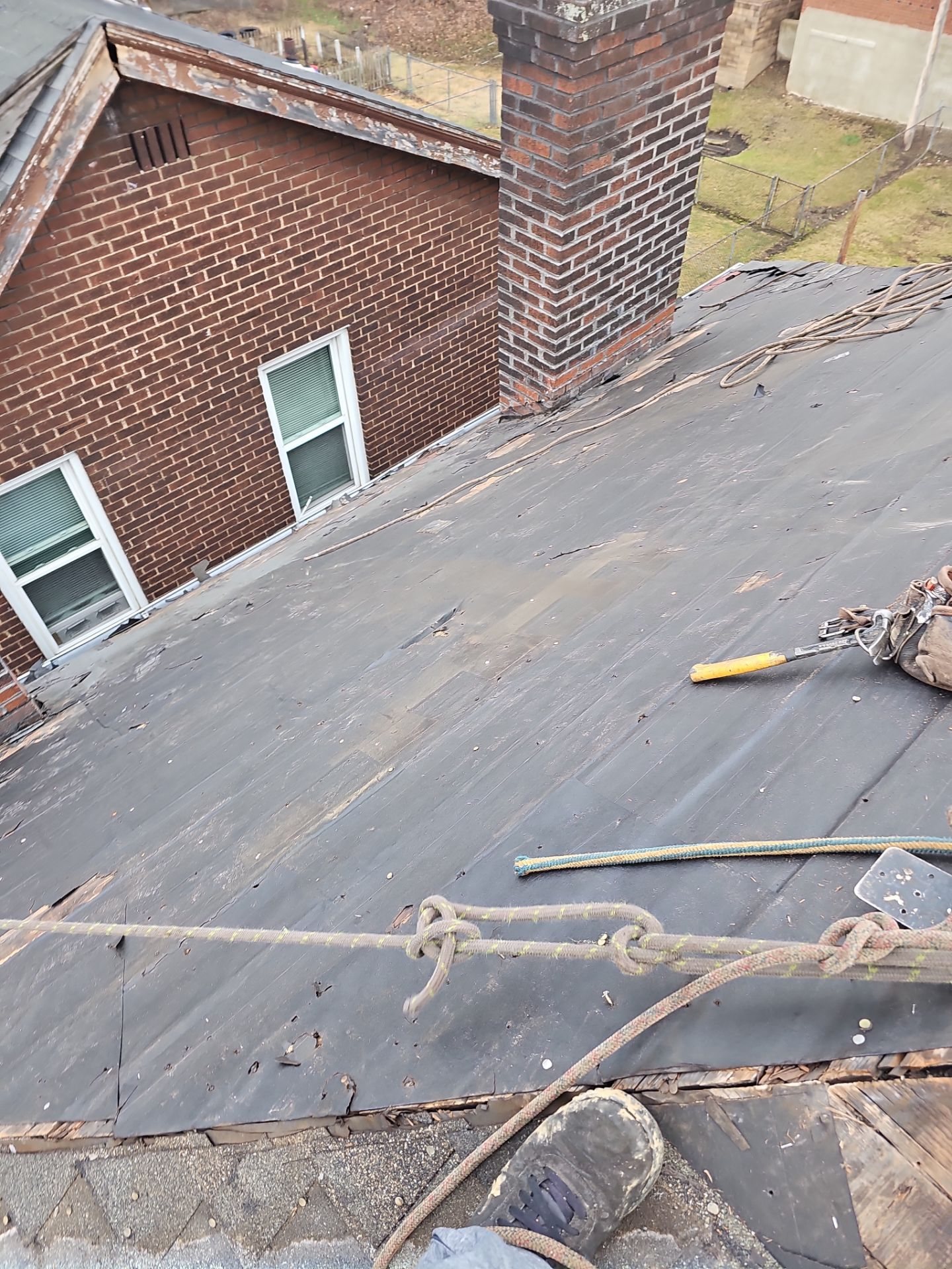 Old worn low slope roofing near a brick chimney in Pittsburgh, Alan Construction