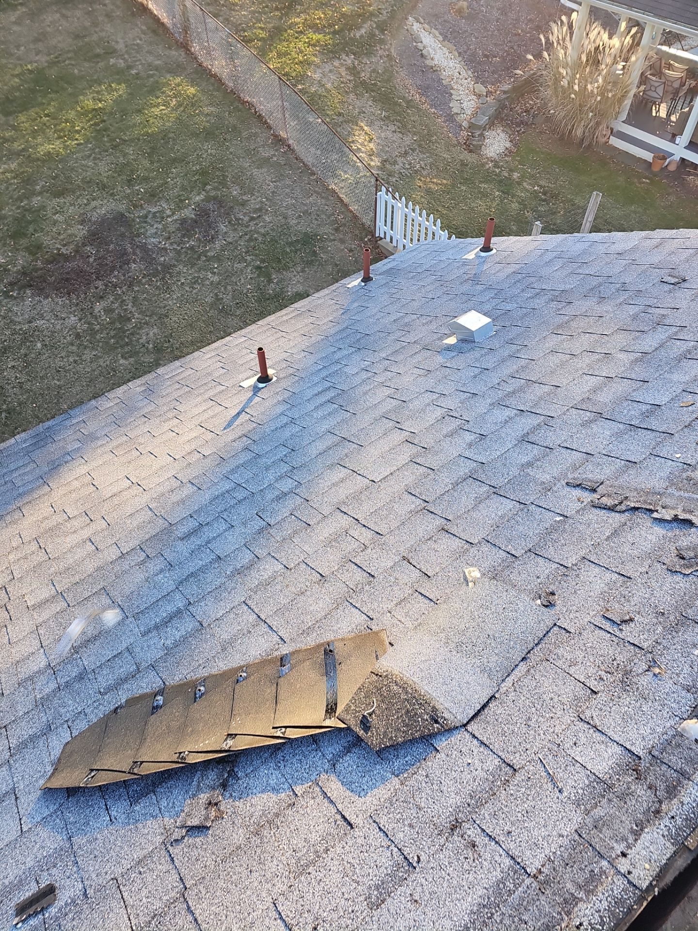 Worn gray shingles with a loose torn piece on the slope in Pittsburgh, Alan Construction