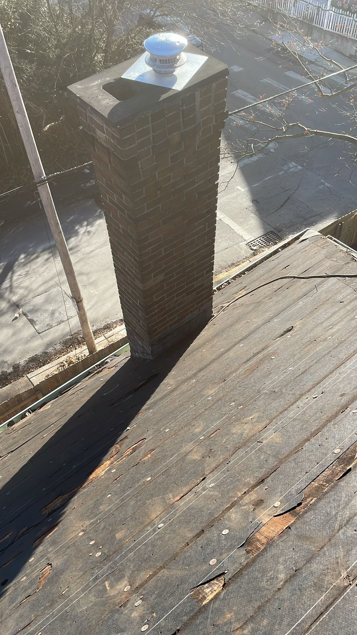 Brick chimney rising from a weathered, worn old roof in Pittsburgh, Alan Construction