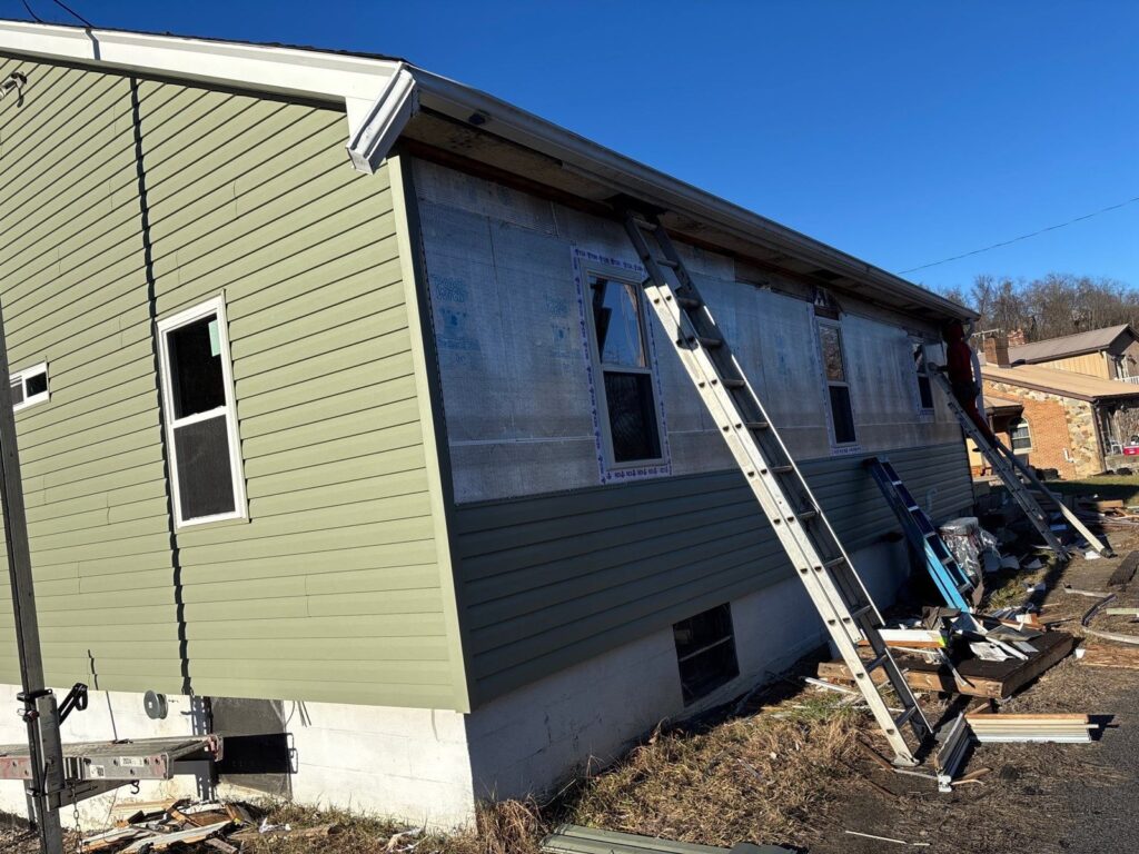 New green vinyl siding going up on a Monongahela home