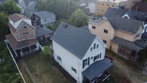Drone view of a white house with a new gray shingle roof in Braddock, Alan Construction