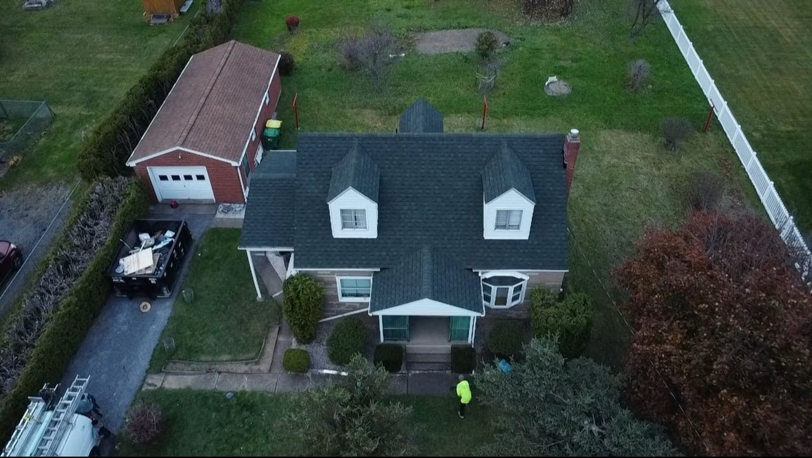 Drone view of a house with dormers and a finished dark shingle roof in Butler, Alan Construction