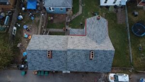 Drone view of a finished gray shingle roof with brick chimneys in Glassport, Alan Construction