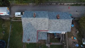 Overhead view of a new gray roof with red drip edge and chimneys in Glassport, Alan Construction