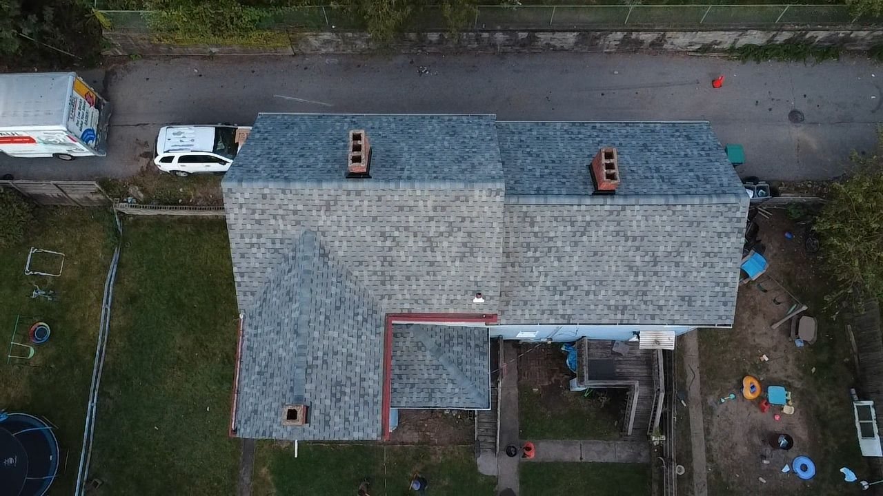 Overhead view of a new gray roof with red drip edge and chimneys in Glassport, Alan Construction