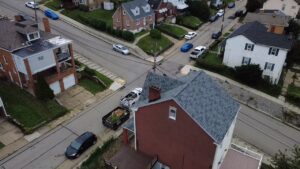 Drone view of a new gray roof with a dumpster at the curb in Pittsburgh, Alan Construction