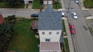 Overhead drone view of a new gray hip roof on a cream house in Pittsburgh, Alan Construction