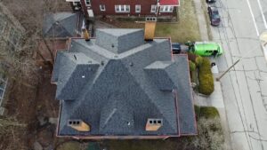 Drone view of a completed gray shingle hip roof on a corner lot in Pittsburgh, Alan Construction