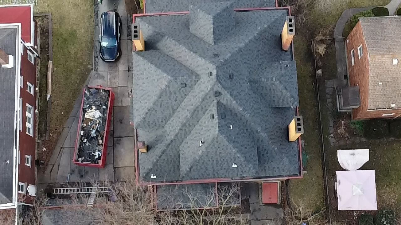 Aerial view of a new gray hip roof with a dumpster in the driveway in Pittsburgh, Alan Construction