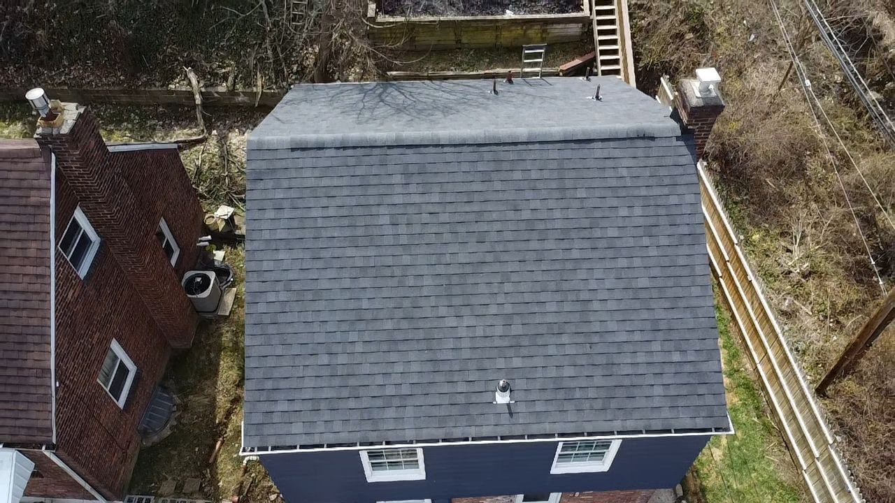 Drone view of a new gray shingle gable roof on a blue house in Pittsburgh, Alan Construction