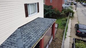 New gray shingles on a lower porch roof beside white siding in Pittsburgh, Alan Construction