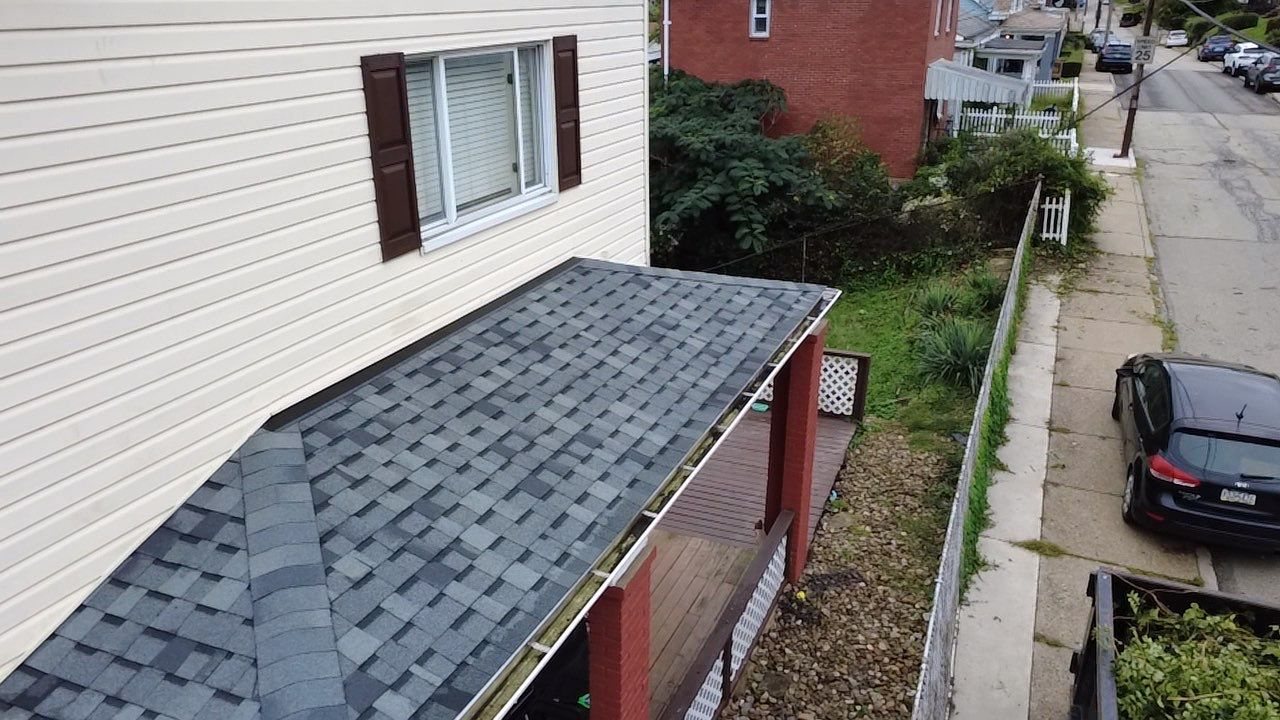 New gray shingles on a lower porch roof beside white siding in Pittsburgh, Alan Construction