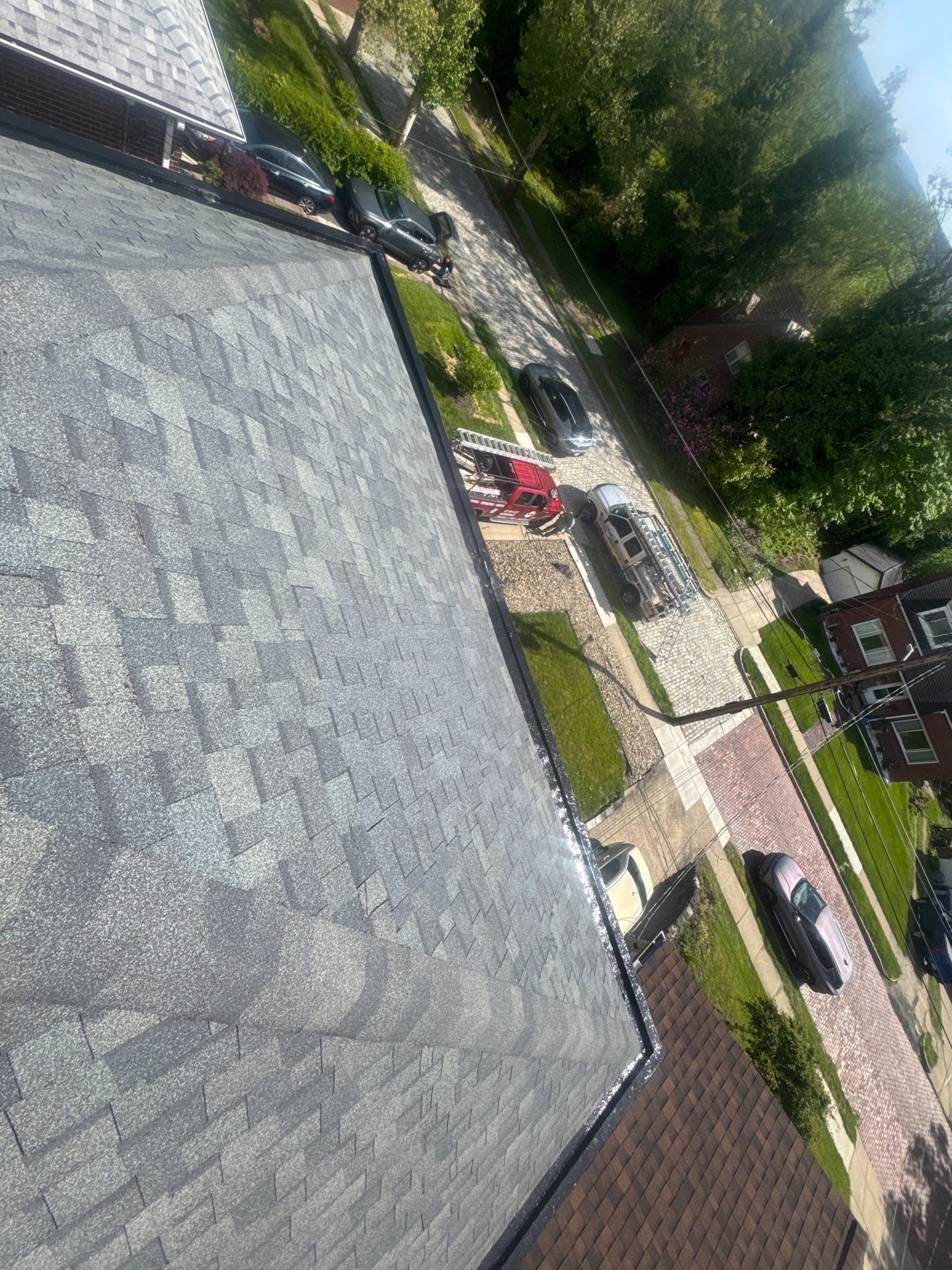 New gray shingles on a roof edge above a street in Pittsburgh, Alan Construction