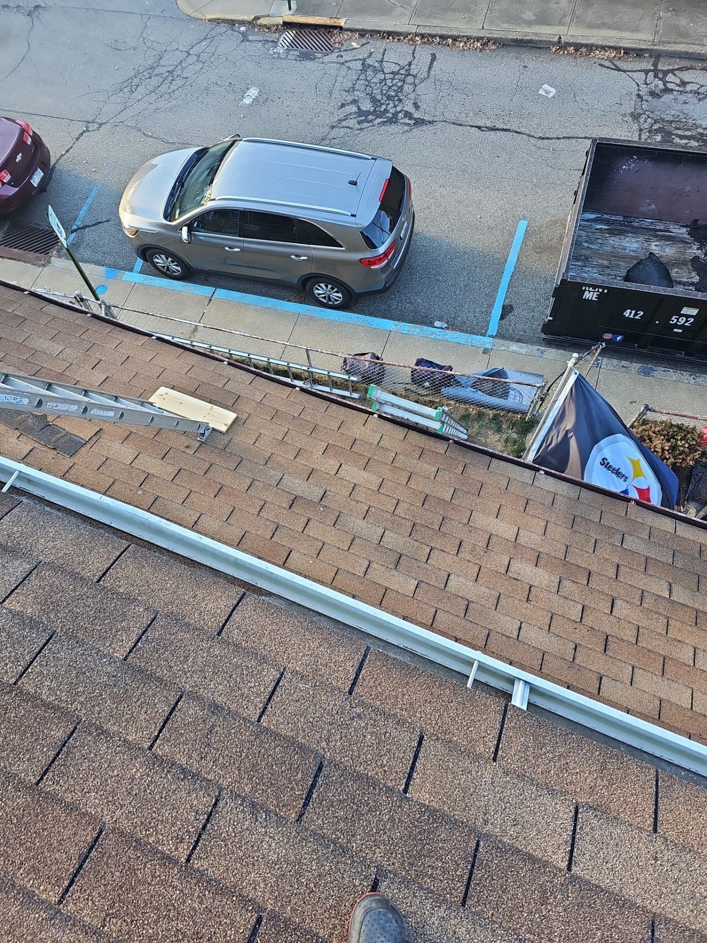 Brown shingles and metal drip edge above a parked car in Pittsburgh, Alan Construction