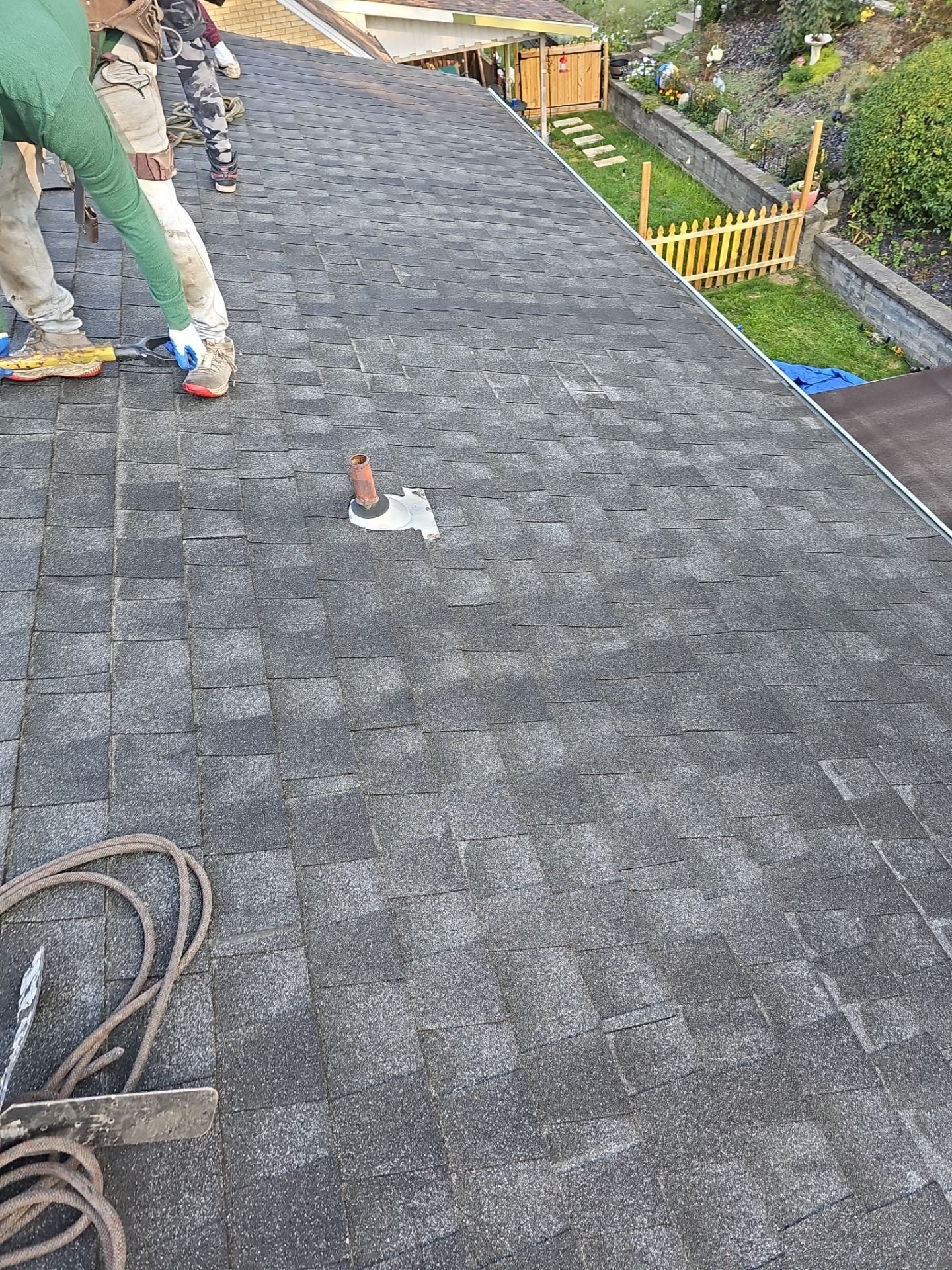 New gray shingles on a slope with an air hose coiled in Pittsburgh, Alan Construction