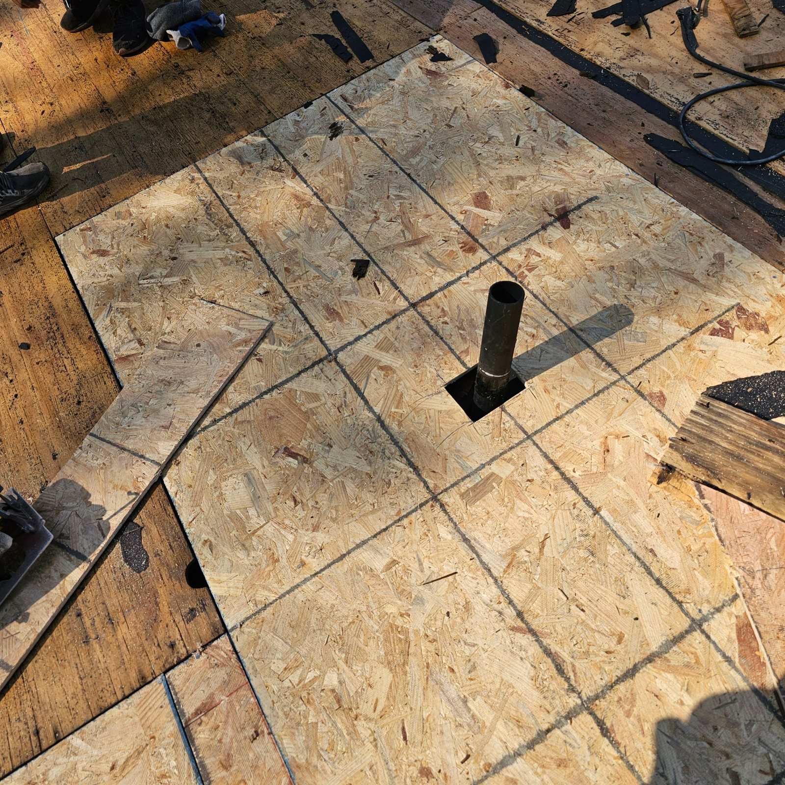 New plywood roof decking around a black pipe vent stack in Natrona Heights, Alan Construction