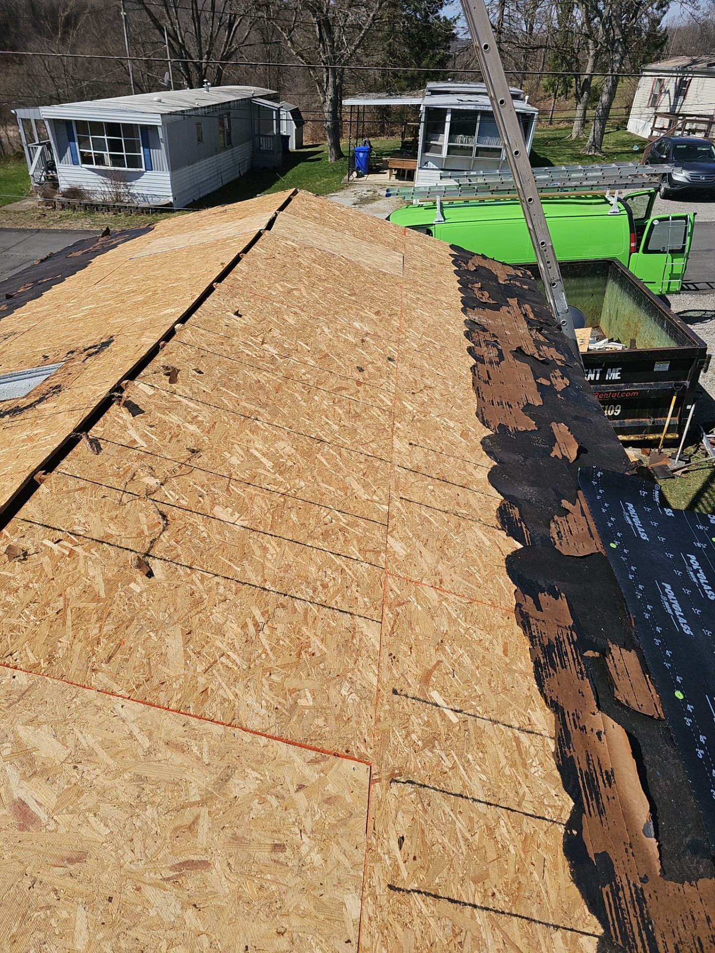 Fresh OSB sheathing covering a roof slope next to old shingles in Oakdale, Alan Construction