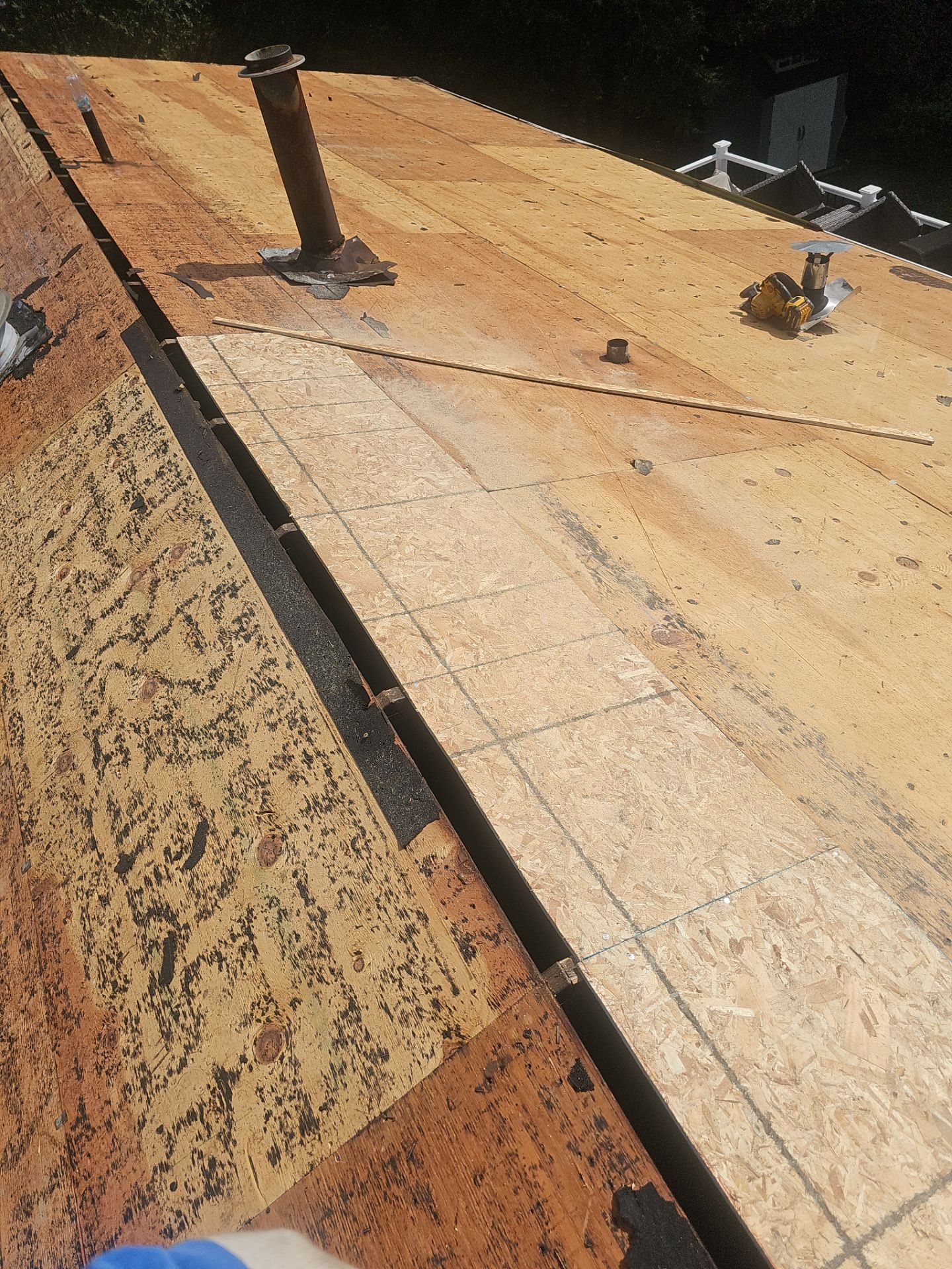New OSB panels beside old plywood decking around a vent pipe in Pittsburgh, Alan Construction