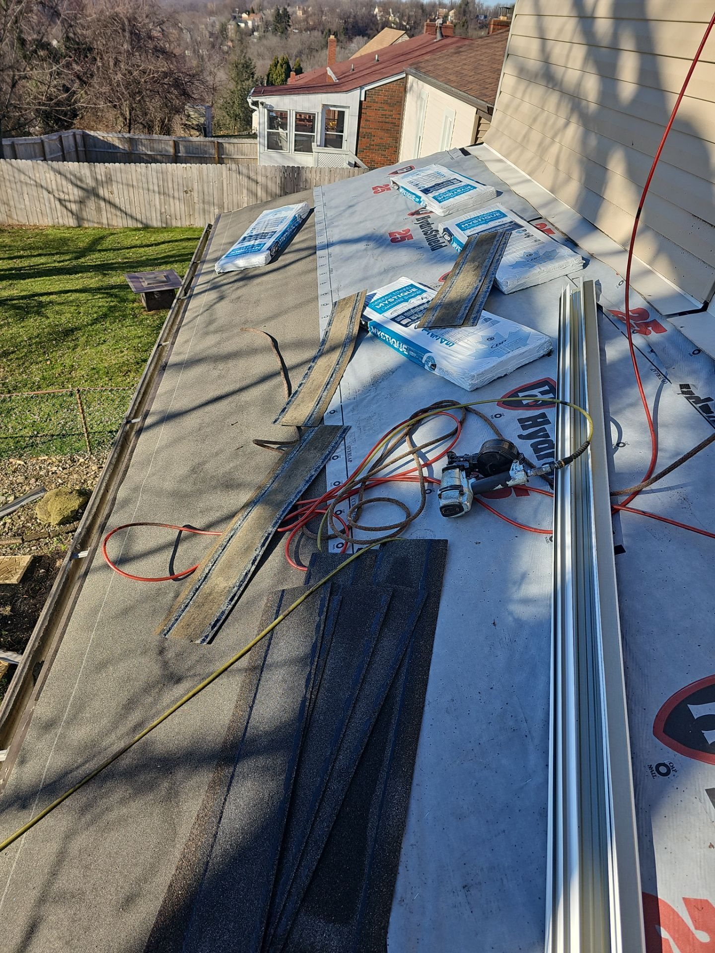Underlayment with drip edge pieces and air hoses on a roof in East Pittsburgh, Alan Construction