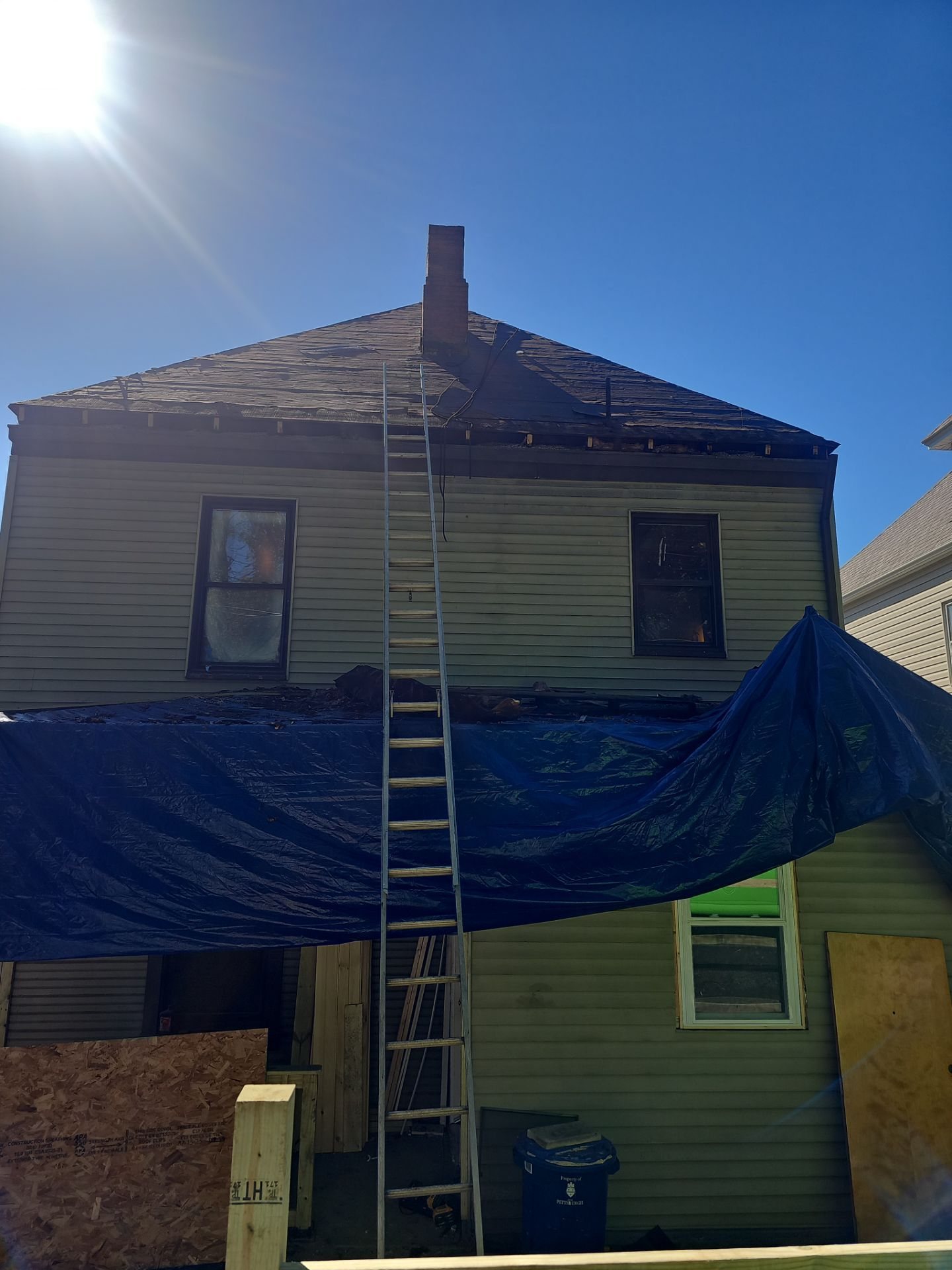 Rear of a house with a ladder to the roof and a tarp below in Pittsburgh, Alan Construction