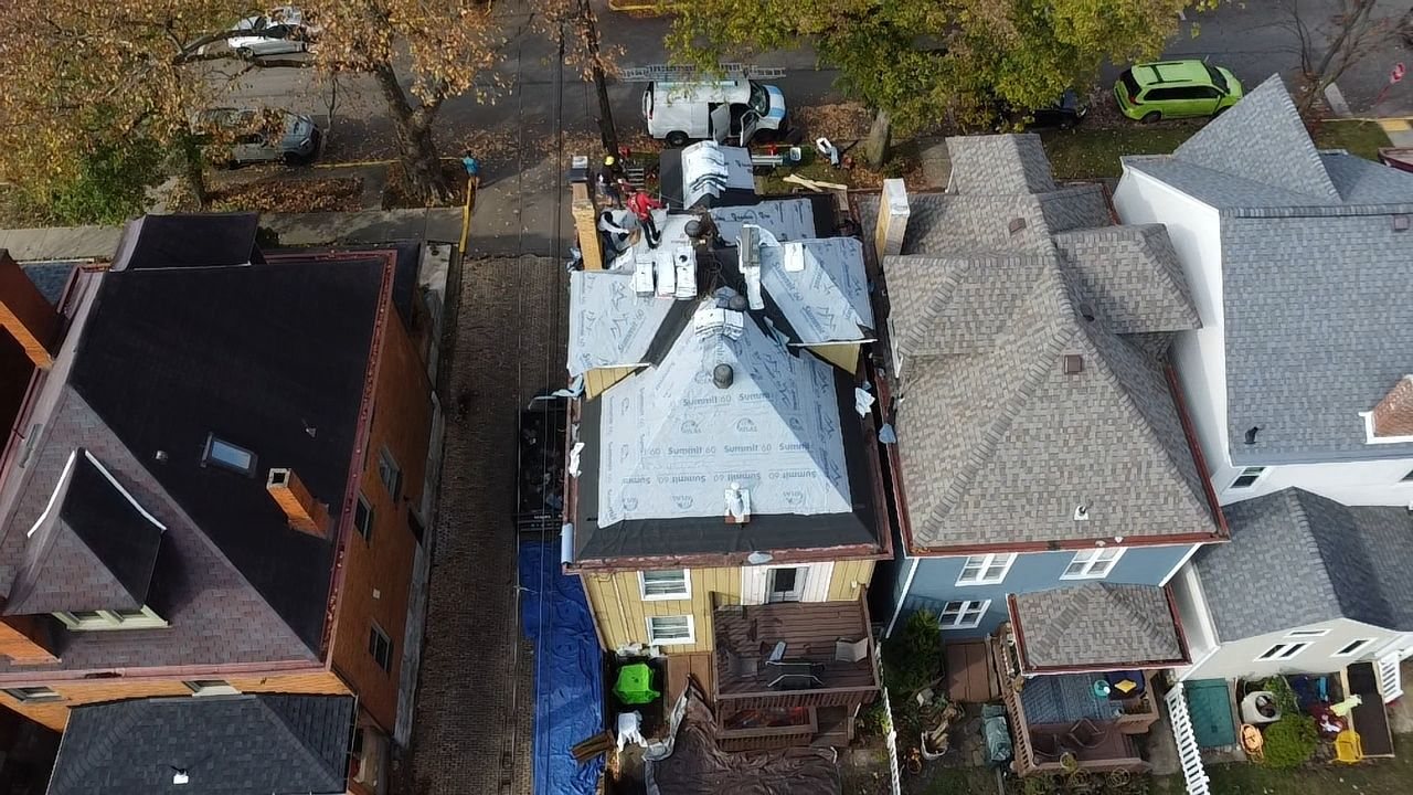 Drone view of a house roof under work between neighboring homes in Pittsburgh, Alan Construction