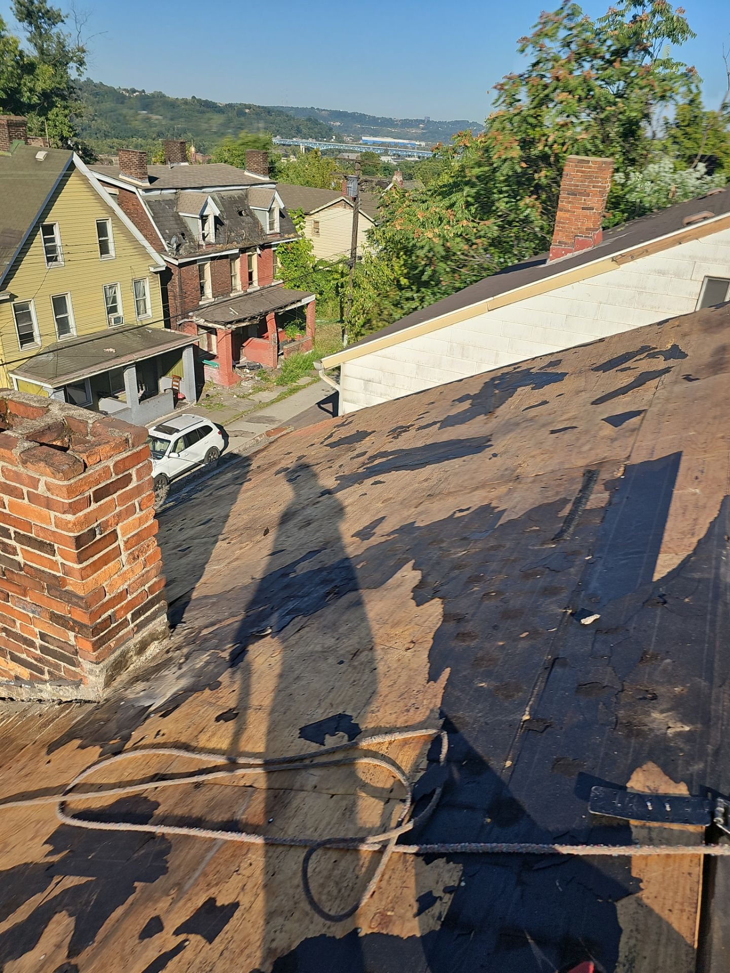 Stripped roof deck beside a brick chimney in Braddock, Alan Construction