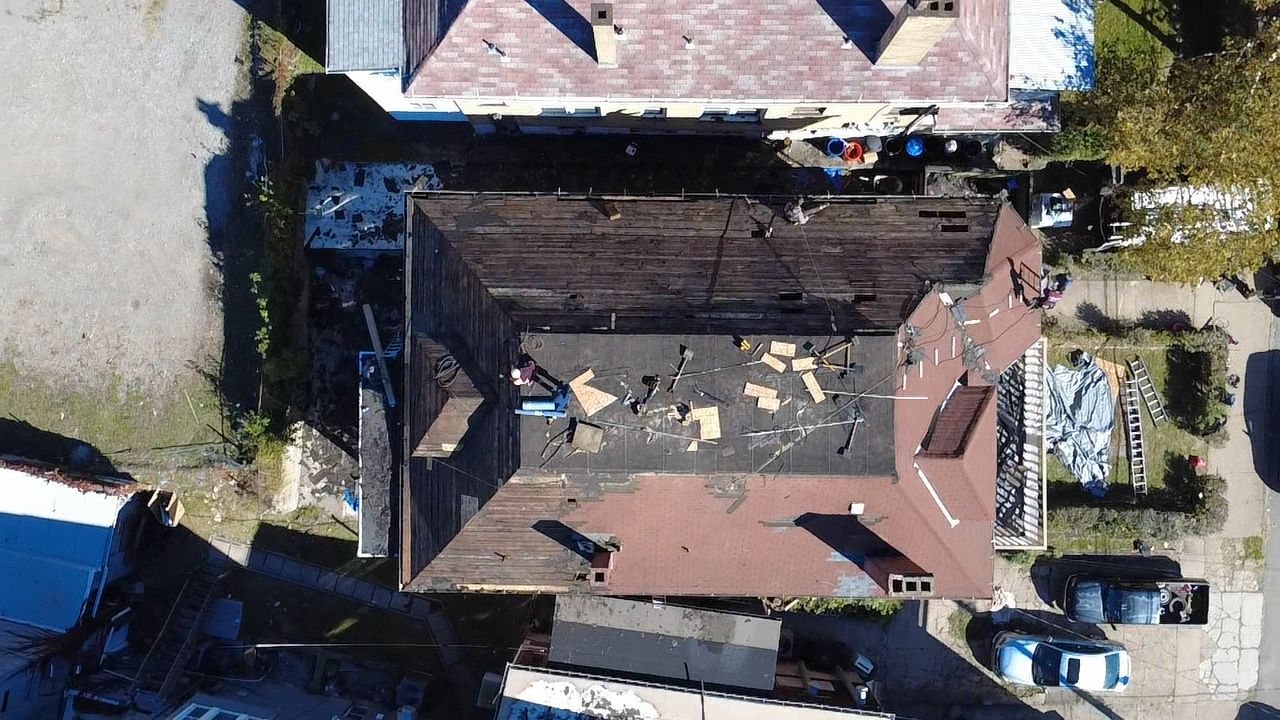 Drone view of a roof partially stripped with debris on the deck in Pittsburgh, Alan Construction