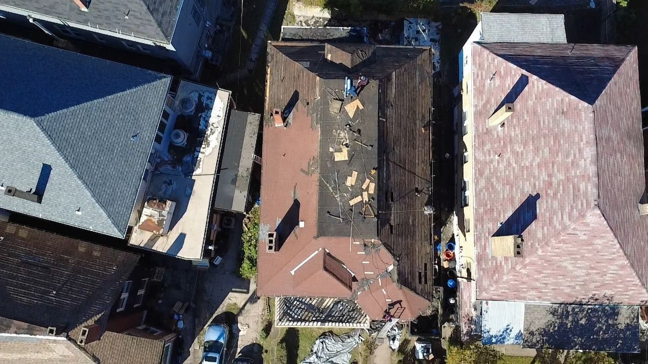 Overhead drone view of a hip roof under tearoff between other homes in Pittsburgh, Alan Construction