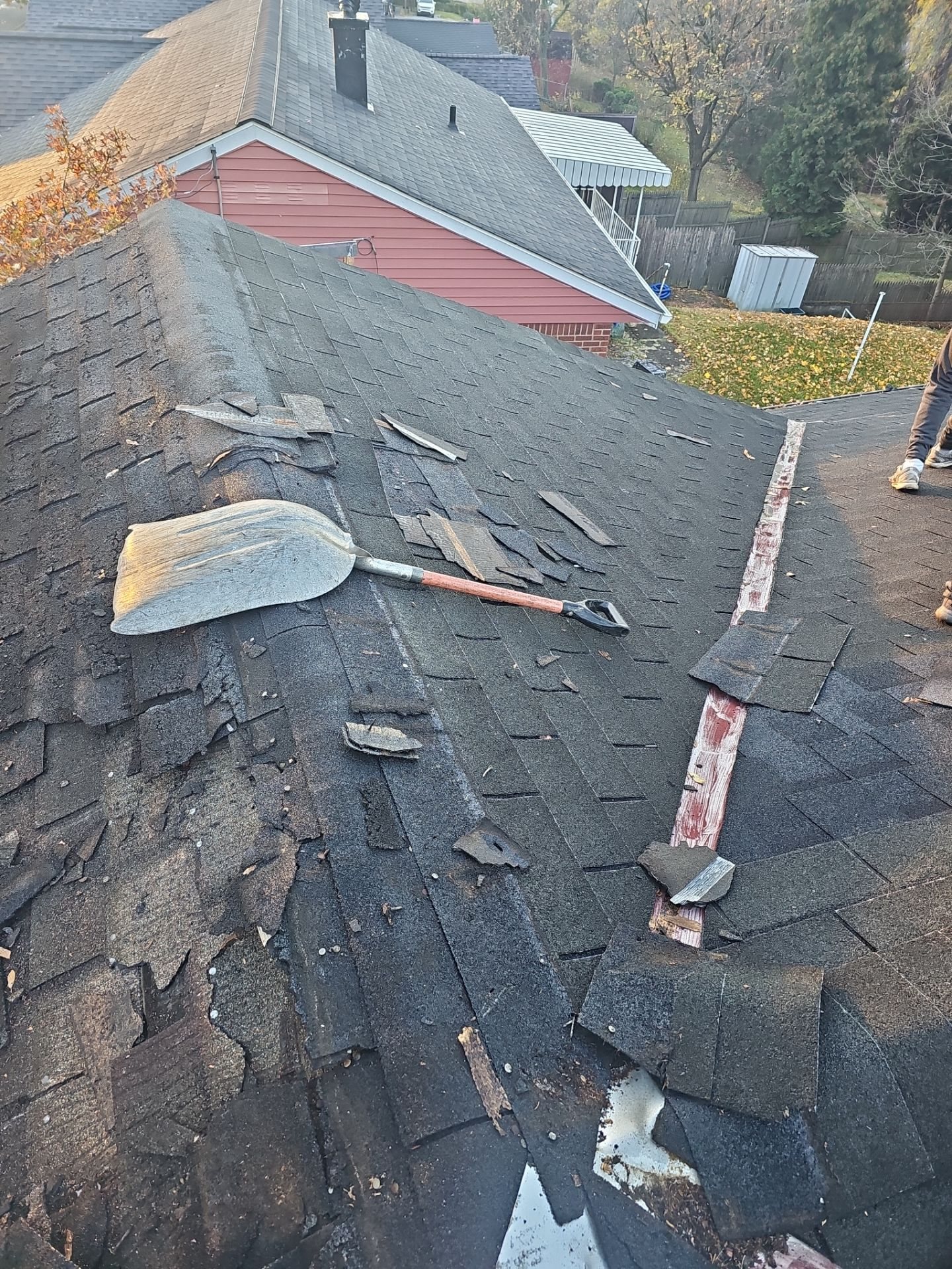 Old shingles partly torn off with a removal shovel on the roof in Pittsburgh, Alan Construction