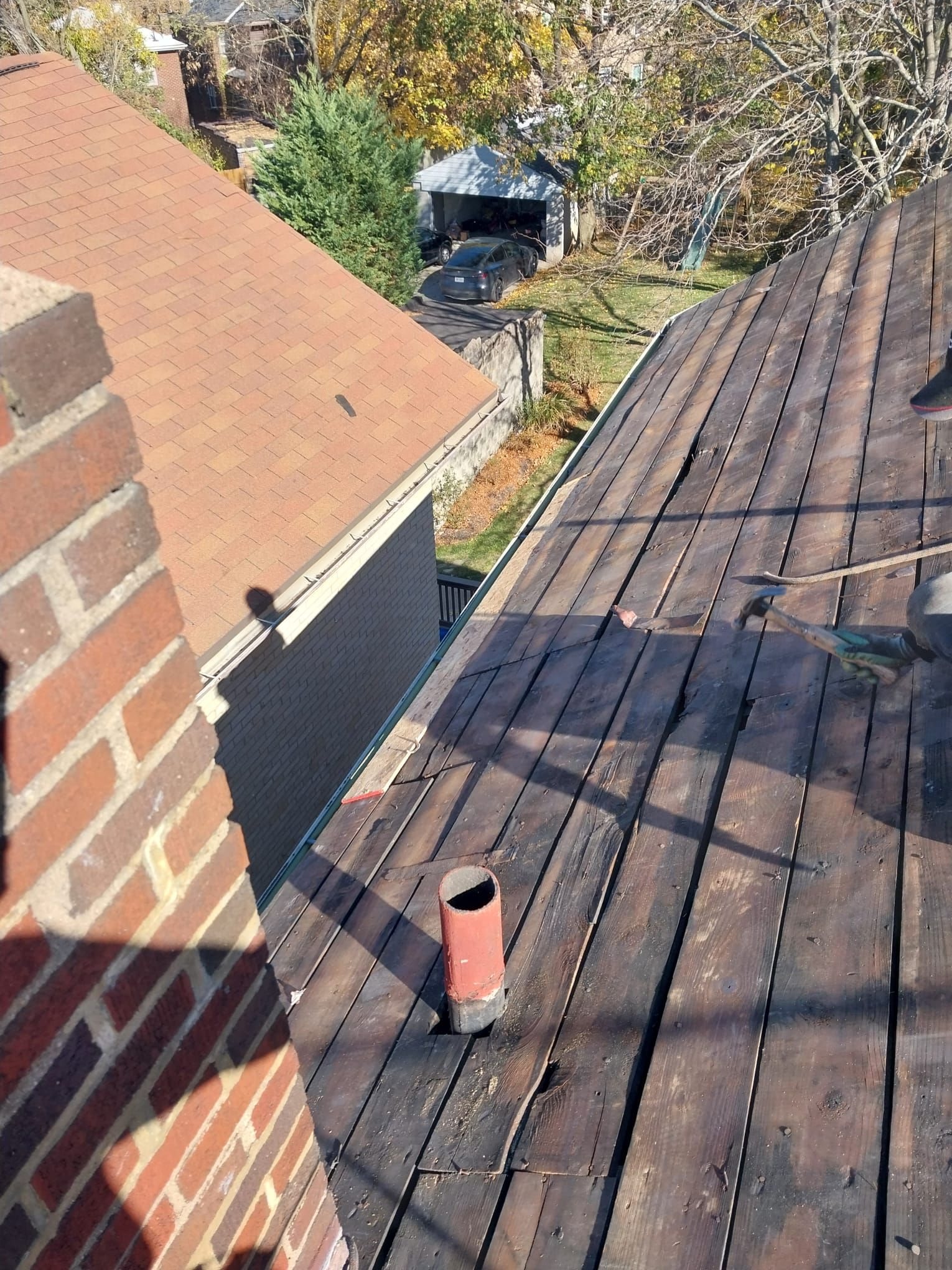 Old board decking exposed after tear off beside a brick chimney in Pittsburgh, Alan Construction