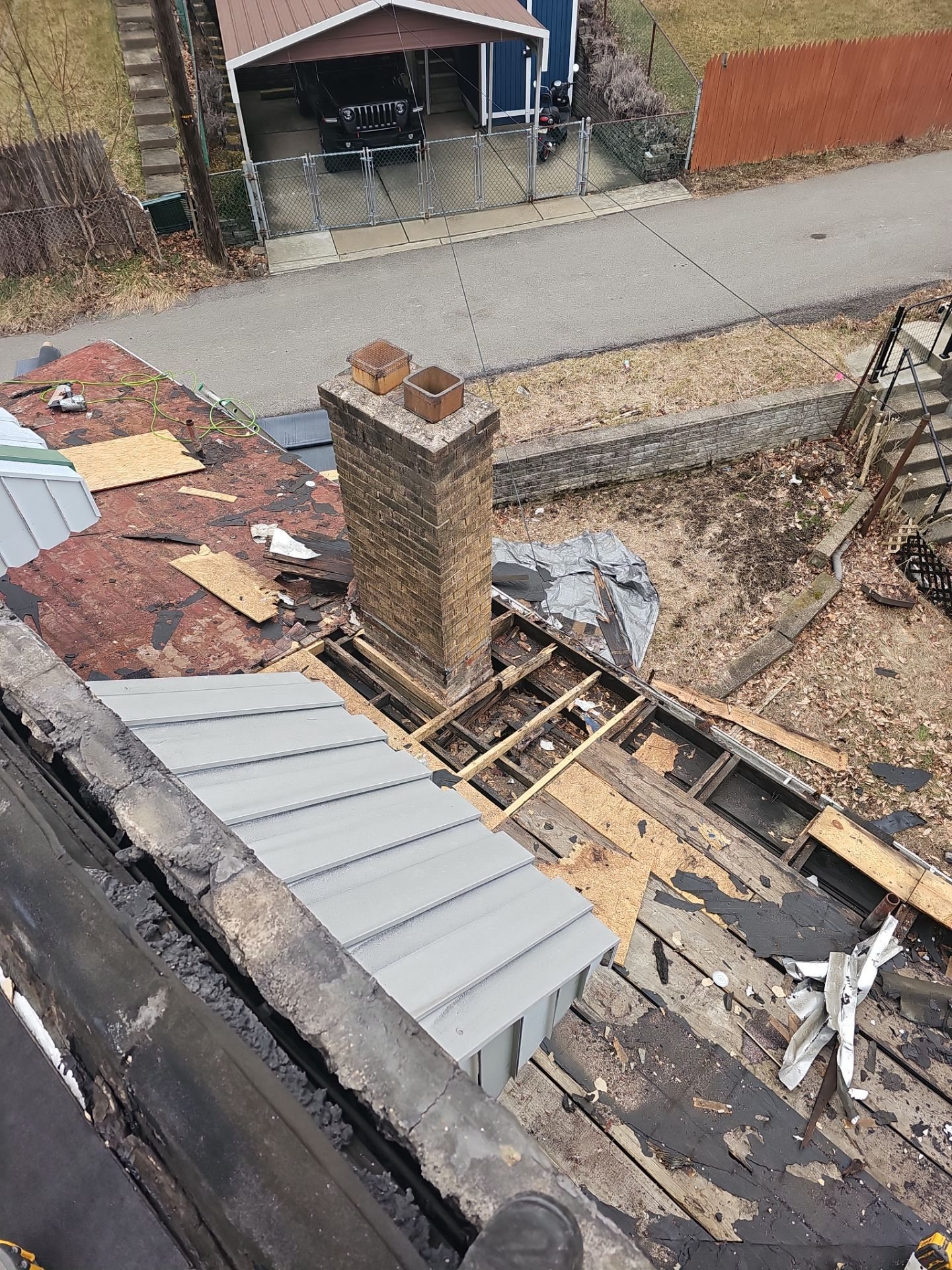 Old roofing torn off around a brick chimney and metal roof in Pittsburgh, Alan Construction