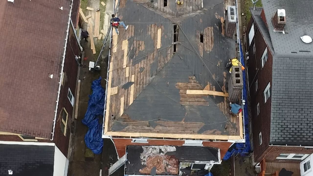 Drone view of a low slope roof mid tear off with tarps in Pittsburgh, Alan Construction